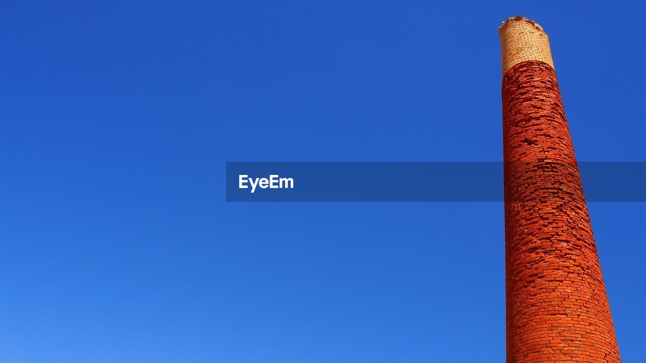 LOW ANGLE VIEW OF SMOKE STACKS AGAINST BLUE SKY