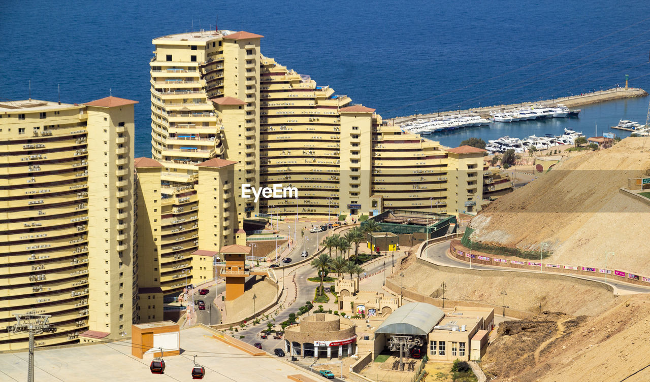 HIGH ANGLE VIEW OF BUILDINGS AND SEA AGAINST CITY