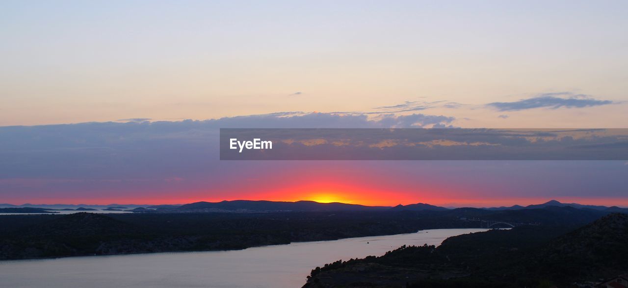 SCENIC VIEW OF SILHOUETTE MOUNTAINS AGAINST ORANGE SKY