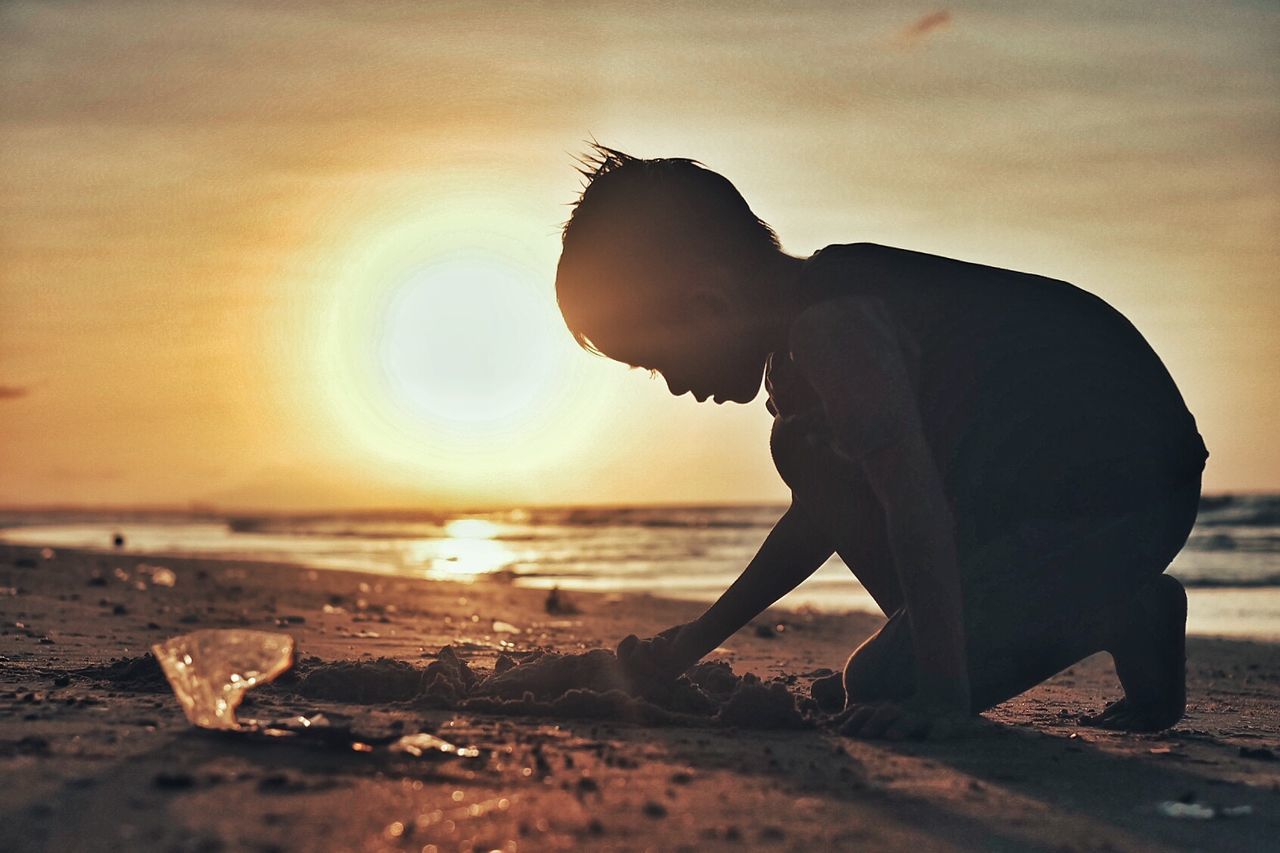 Boy playing on beach at sunset