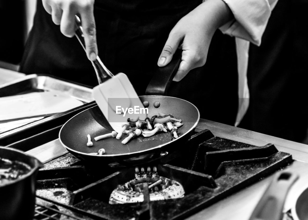 MIDSECTION OF MAN PREPARING FOOD AT KITCHEN