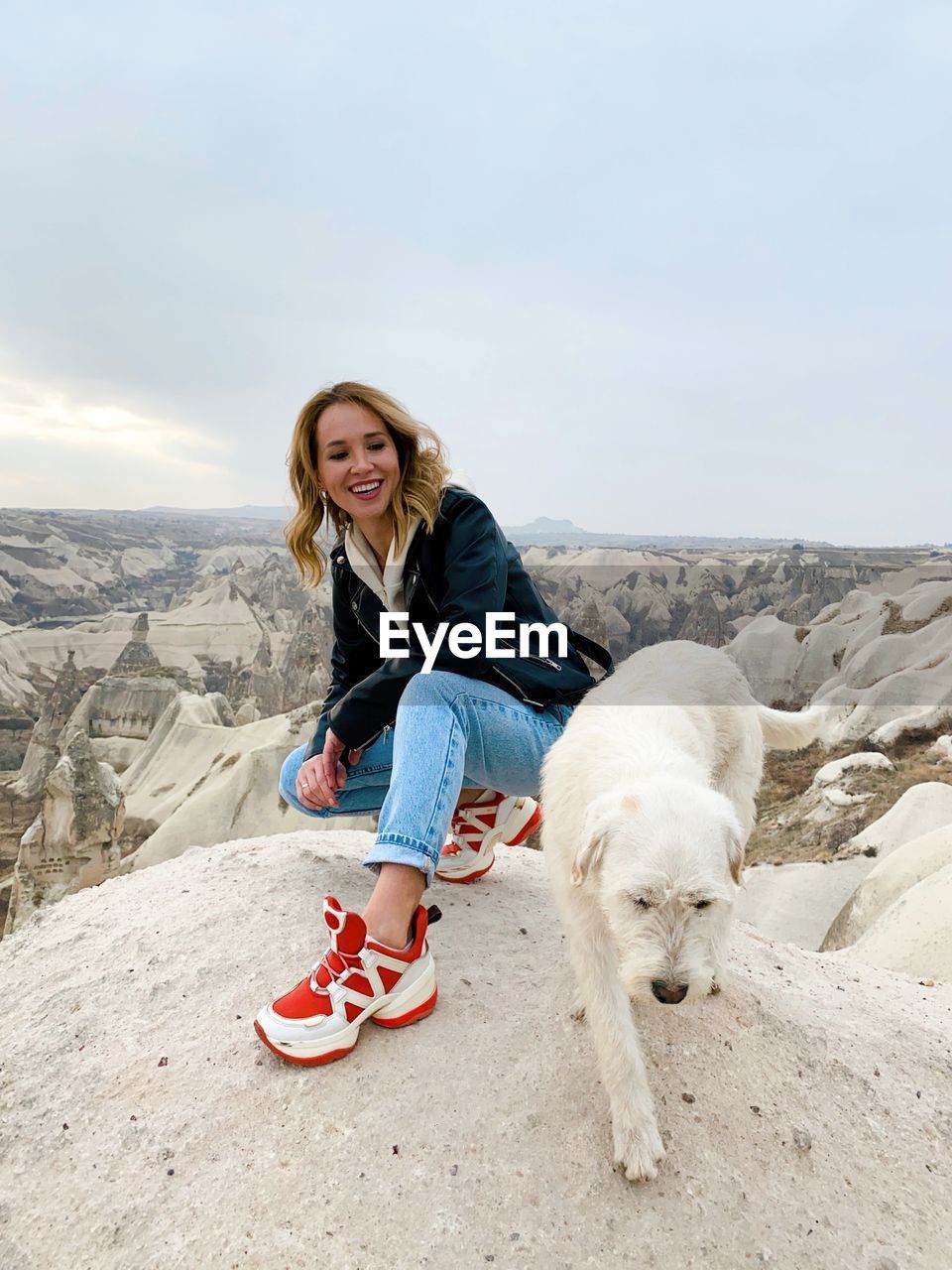 Portrait of woman with dog against sky