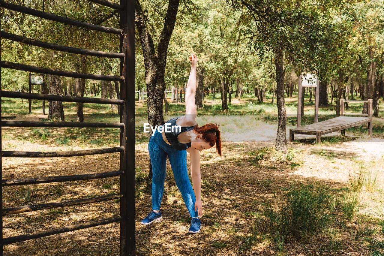 full length of woman with arms outstretched standing on field