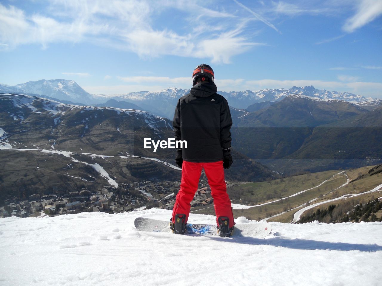 Rear view of young man standing by mountains against sky