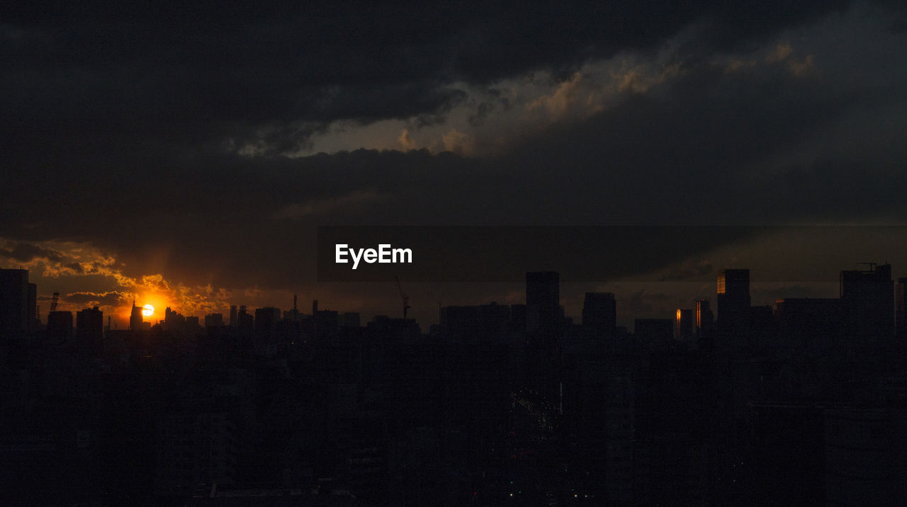 Silhouette cityscape against sky at night