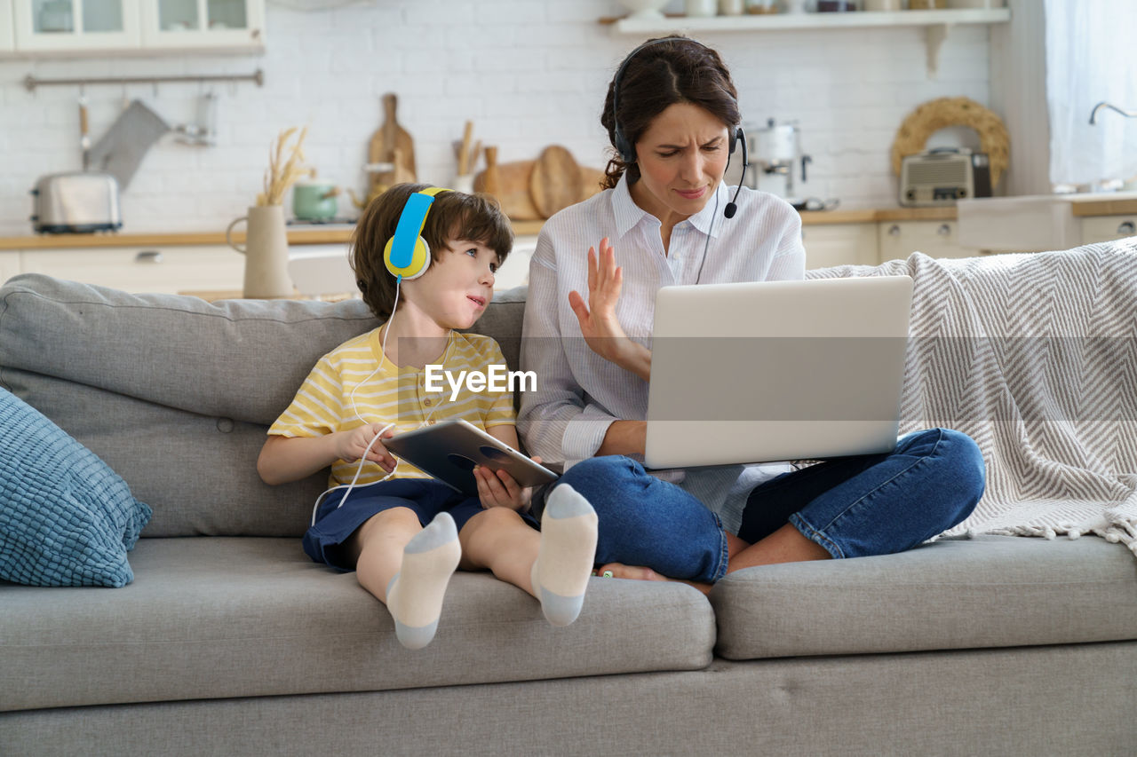 Mother working from home while siting with son at home