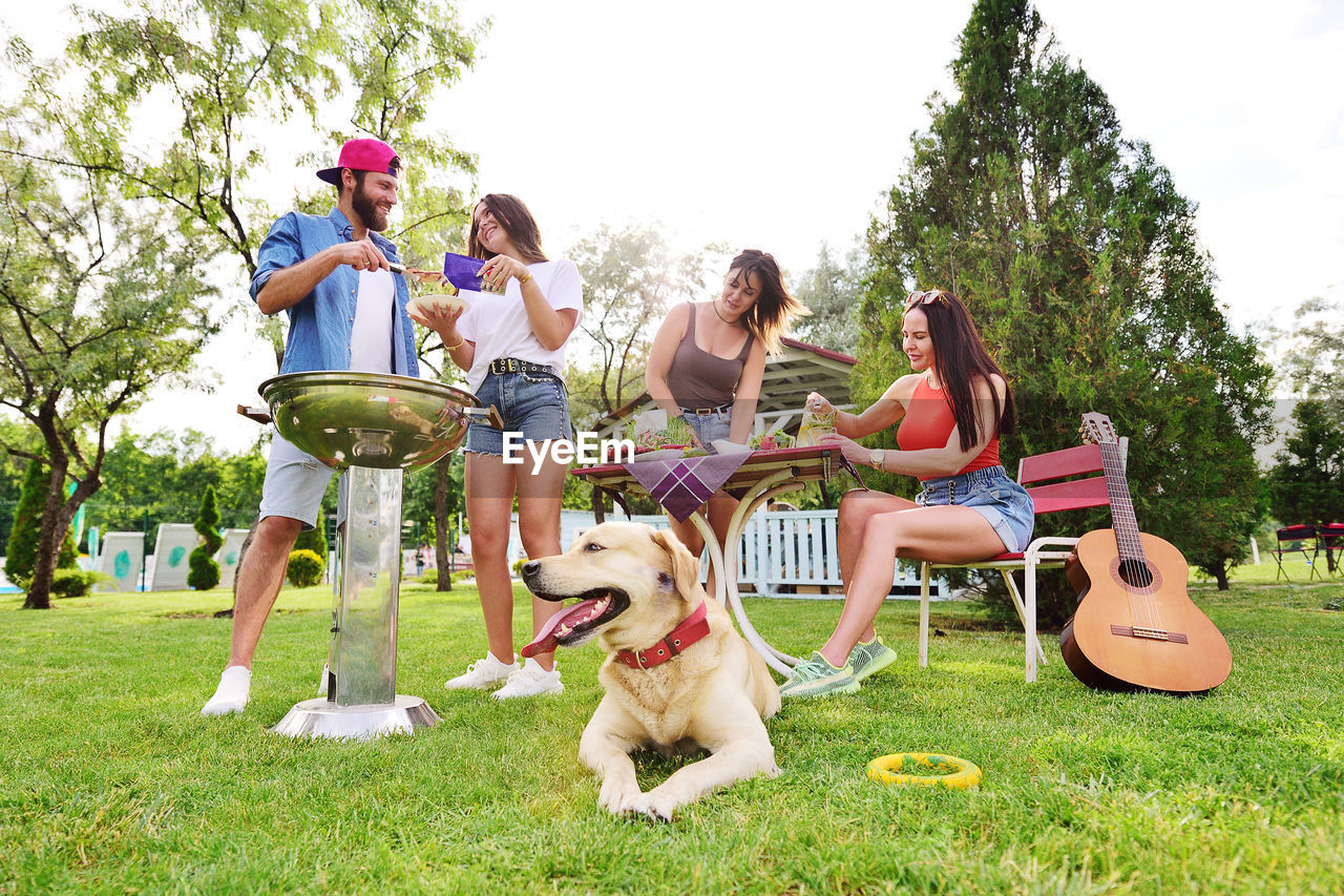 Group of friends in the park at a picnic are barbecued, chatting