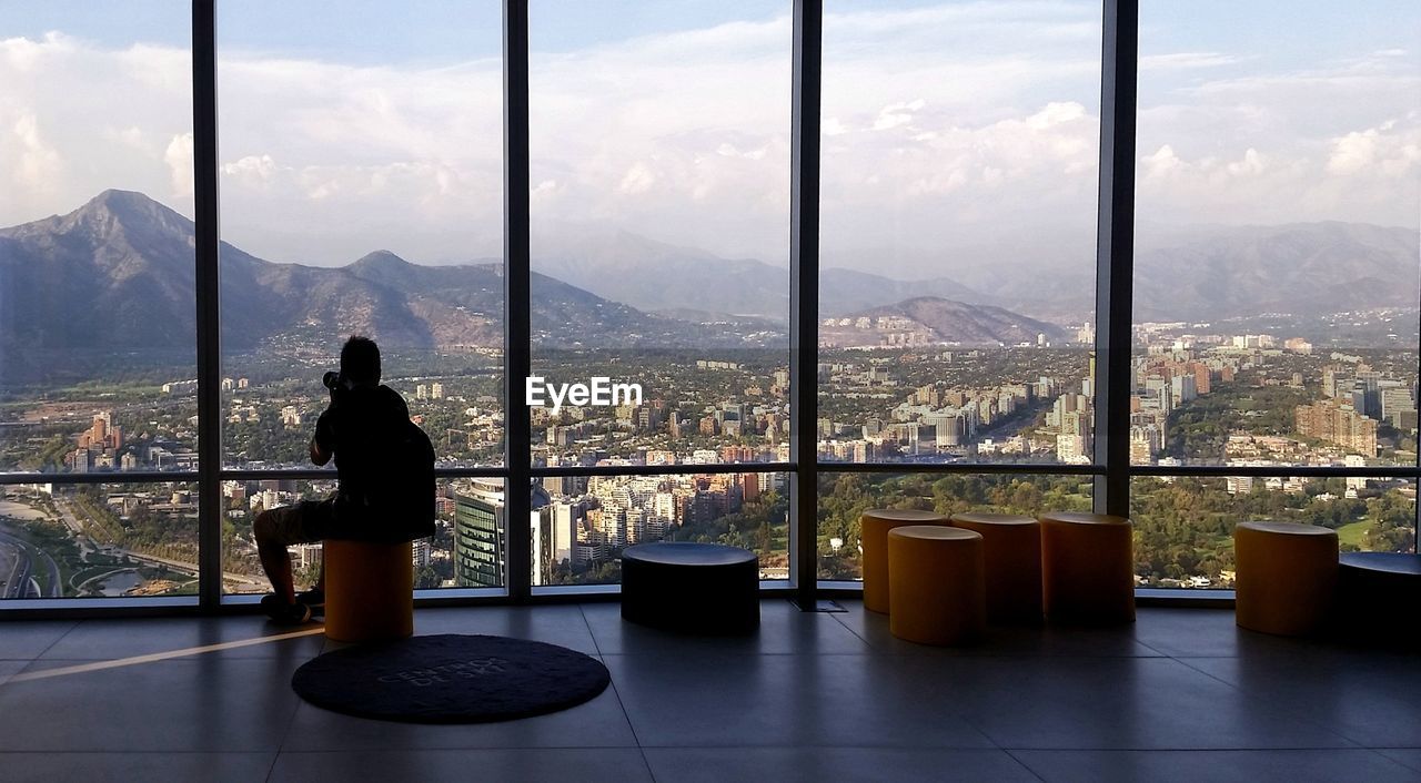 MAN STANDING BY WINDOW IN CITY