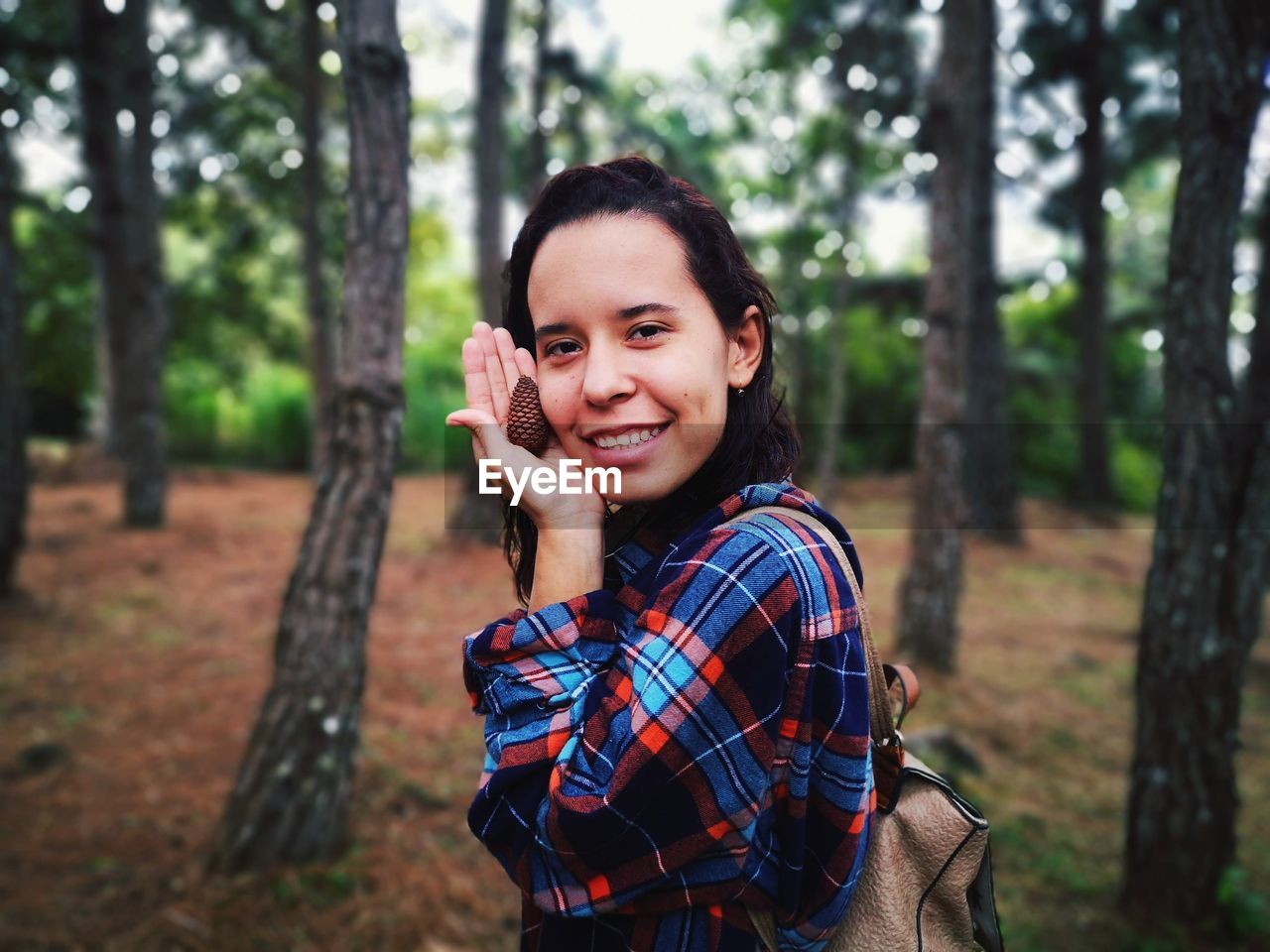 Portrait of smiling woman holding pine cone