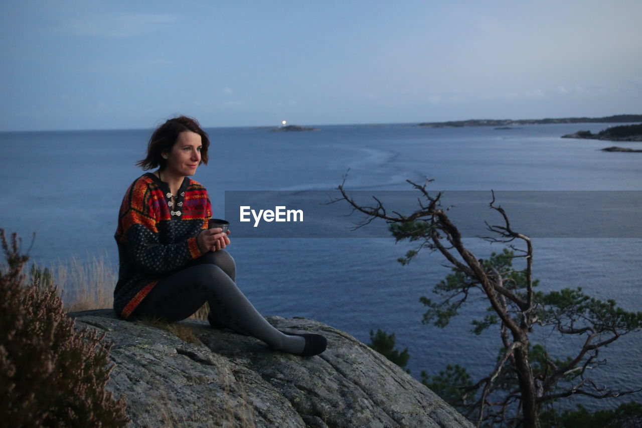 Woman sitting on rock on beach