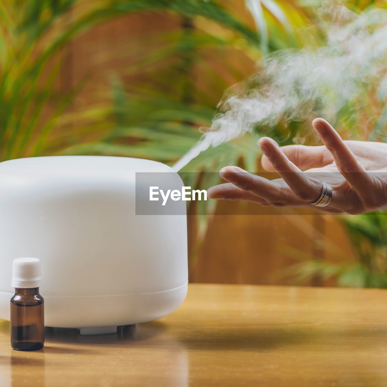 Woman enjoying aroma therapy steam scent from home essential oil diffuser or air humidifier.
