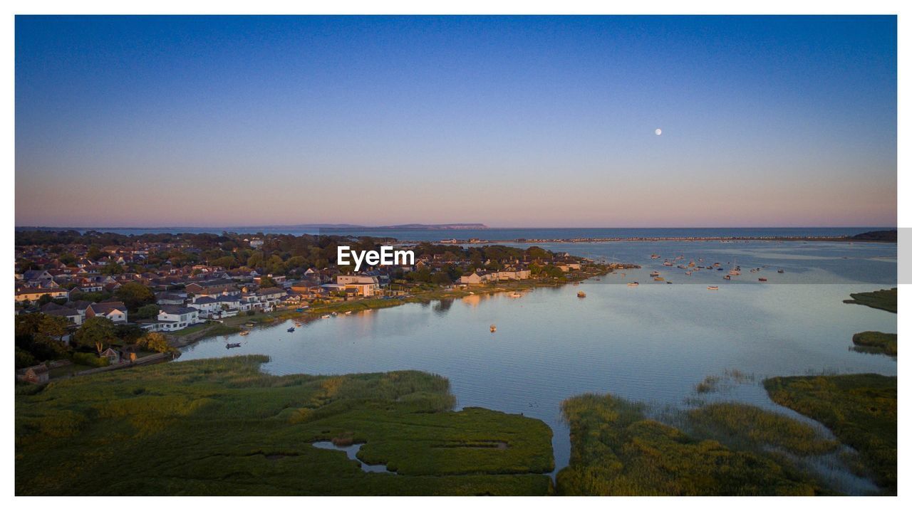 AERIAL VIEW OF CITY AND SEA AGAINST CLEAR SKY