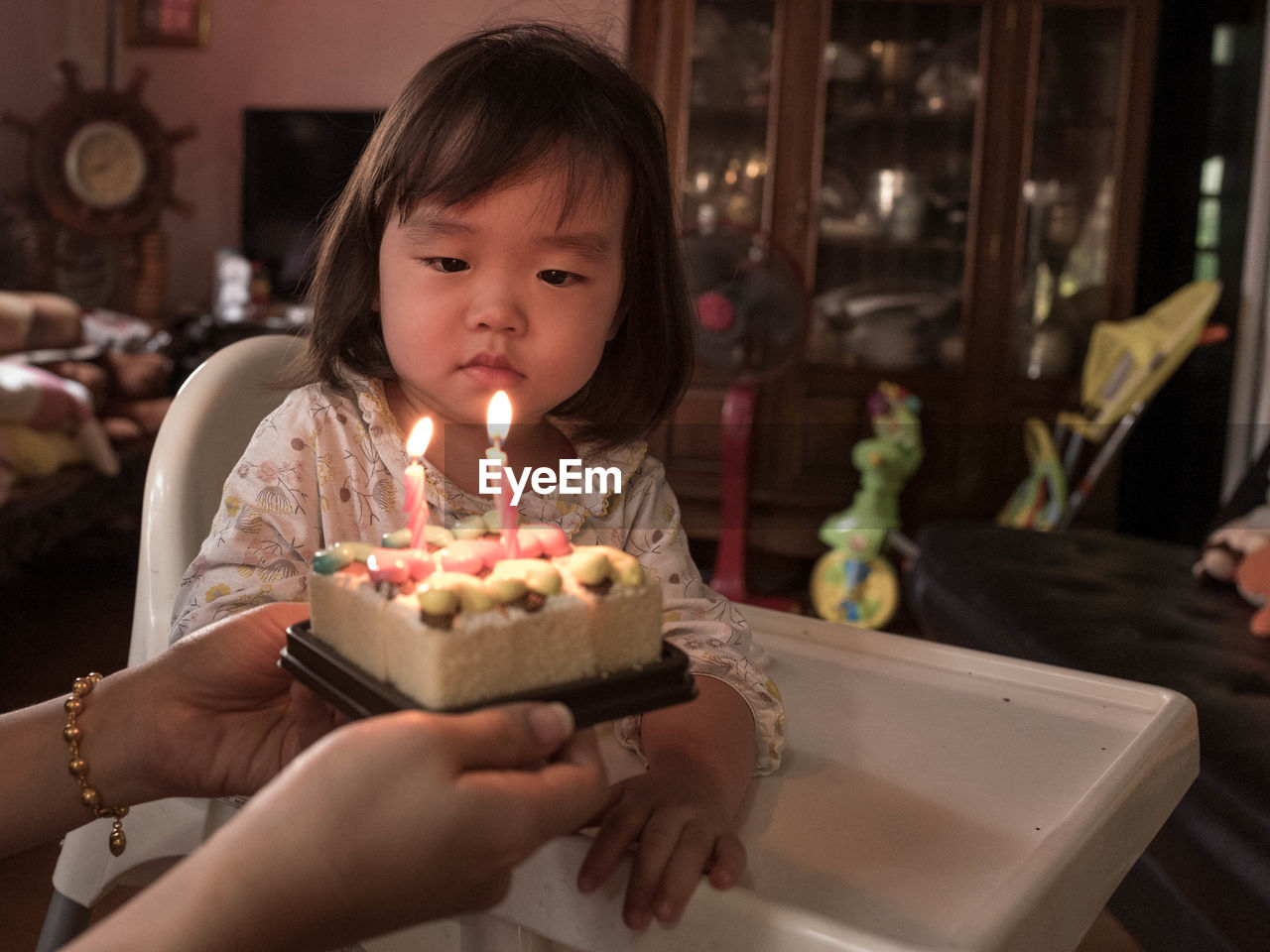 Cropped hands of mother holding birthday cake by daughter at home