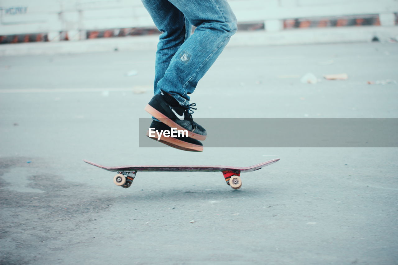 LOW SECTION OF PERSON STANDING ON SKATEBOARD