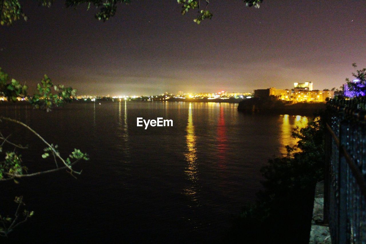 RIVER BY ILLUMINATED TREE AGAINST SKY