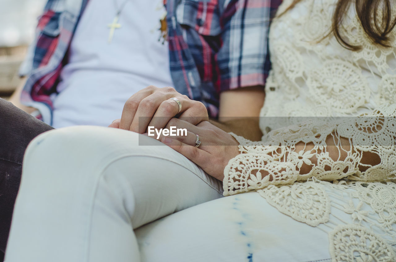 Midsection of couple sitting on bench