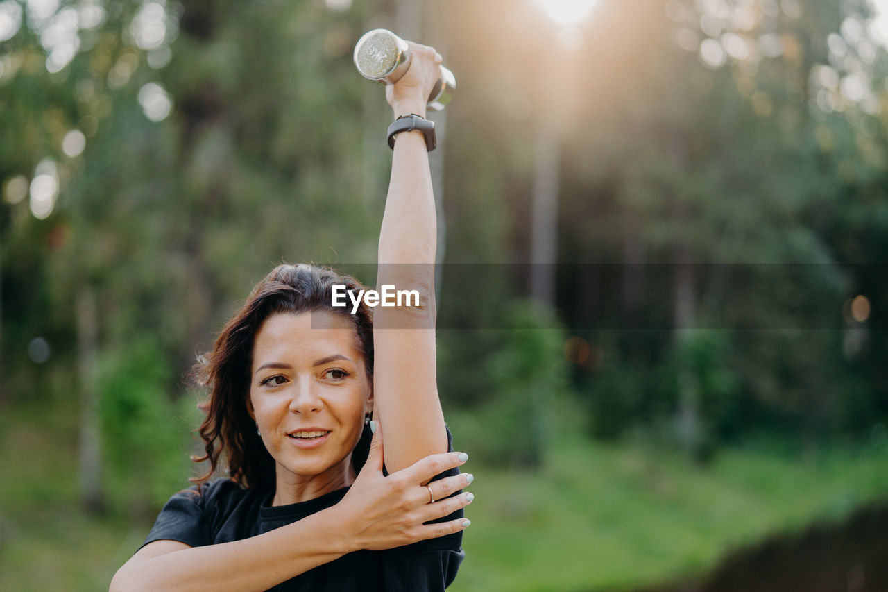 Smiling woman exercising while standing outdoors