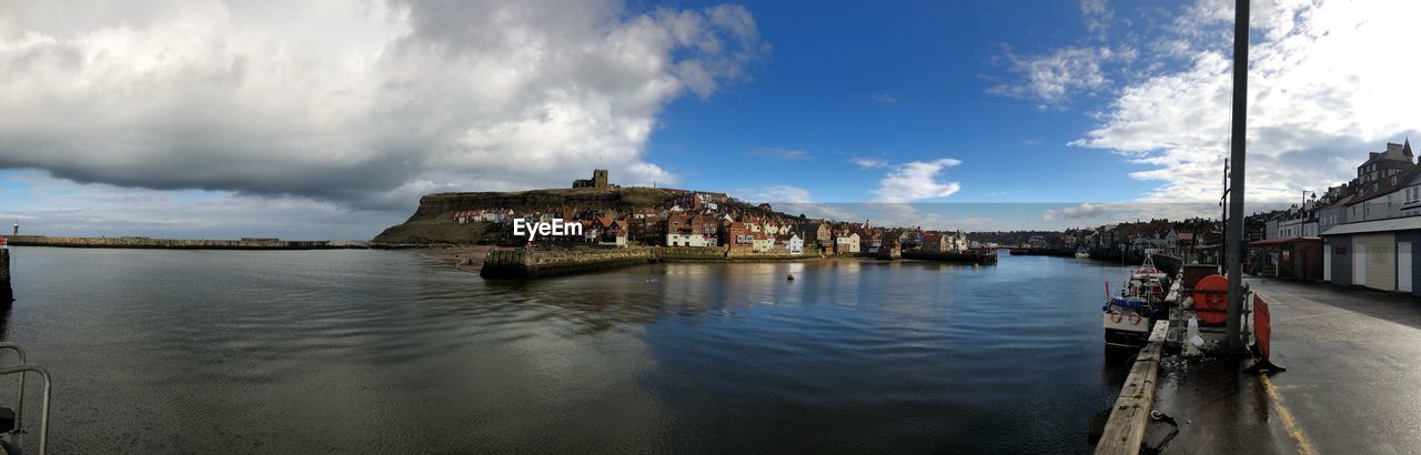 Panoramic view of buildings along with river against sky