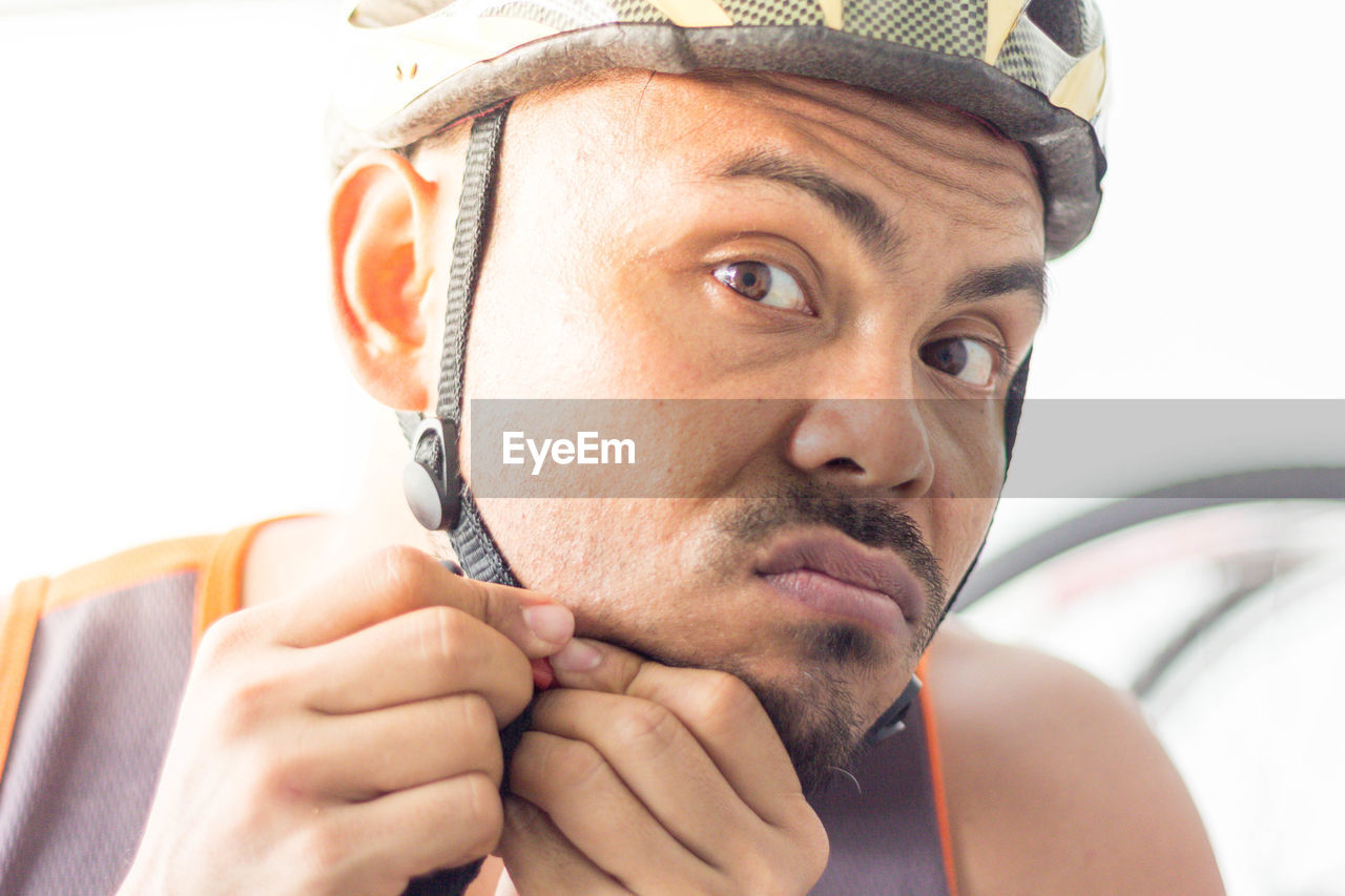 Close-up portrait of man adjusting helmet