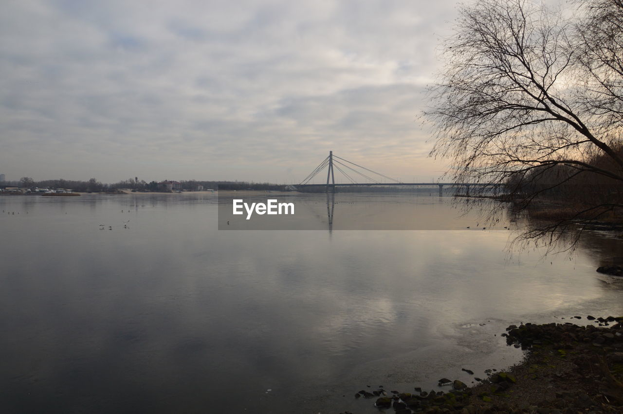 REFLECTION OF BRIDGE AND CLOUDS IN WATER