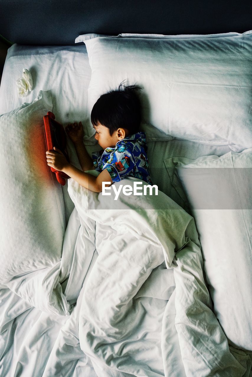 High angle view of boy resting on bed at home