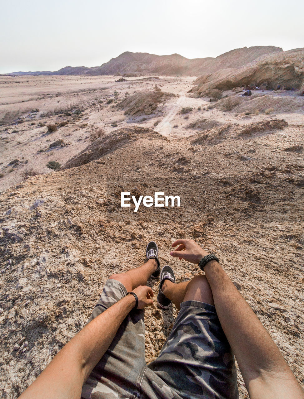 Low section of man on land against sky