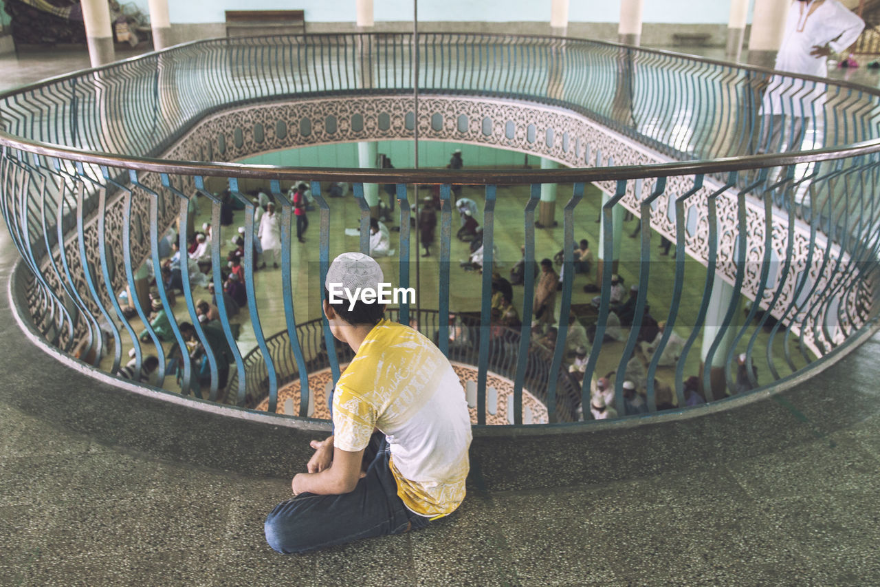 High angle view of man looking at people praying in mosque