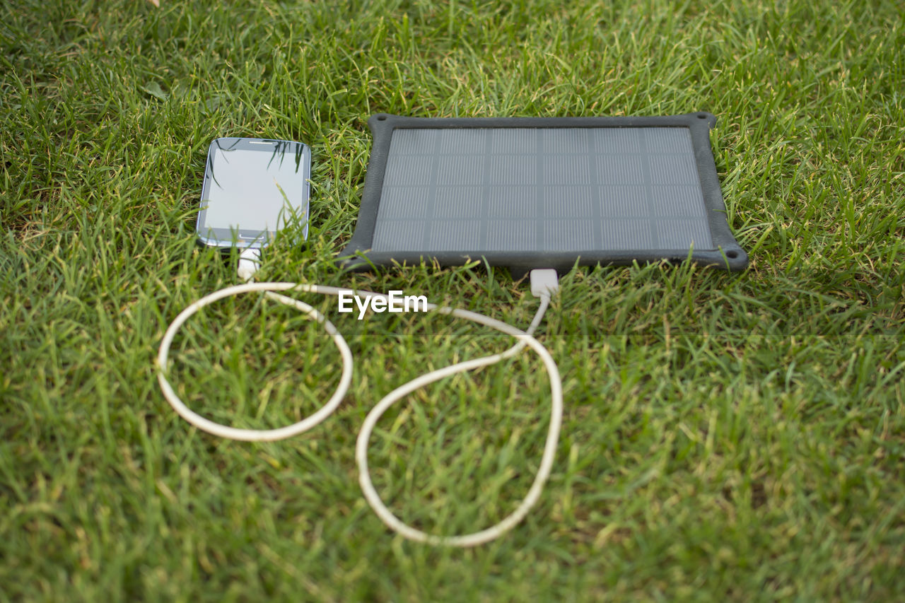 Mobile phone charging on grassy field