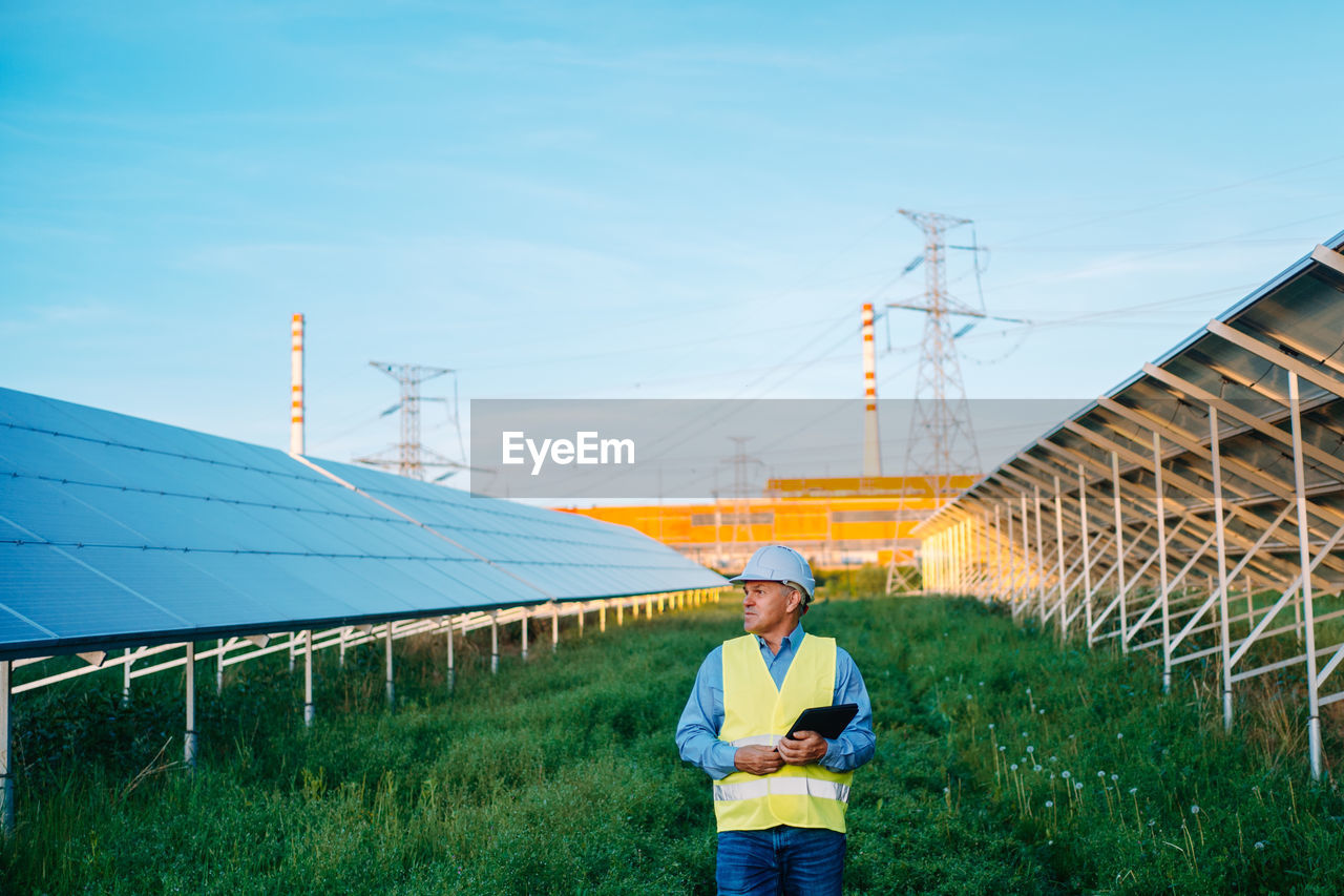 Engineer looking away standing at solar plant