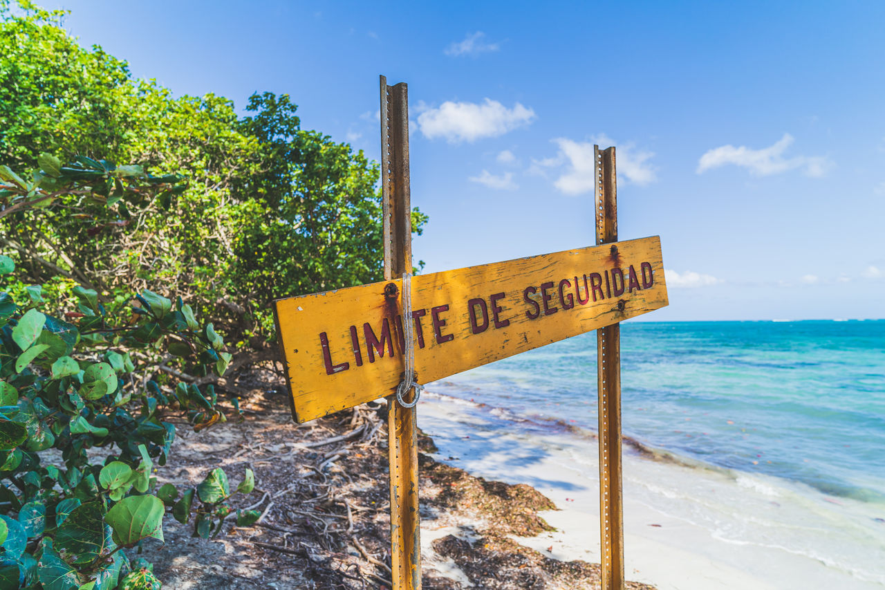 INFORMATION SIGN ON WOODEN POST BY SEA