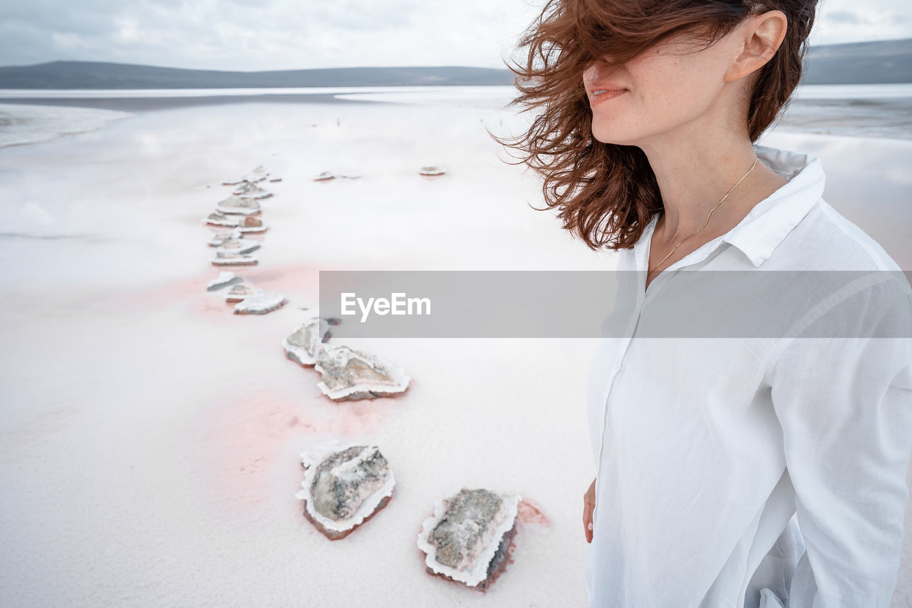 WOMAN STANDING AT BEACH