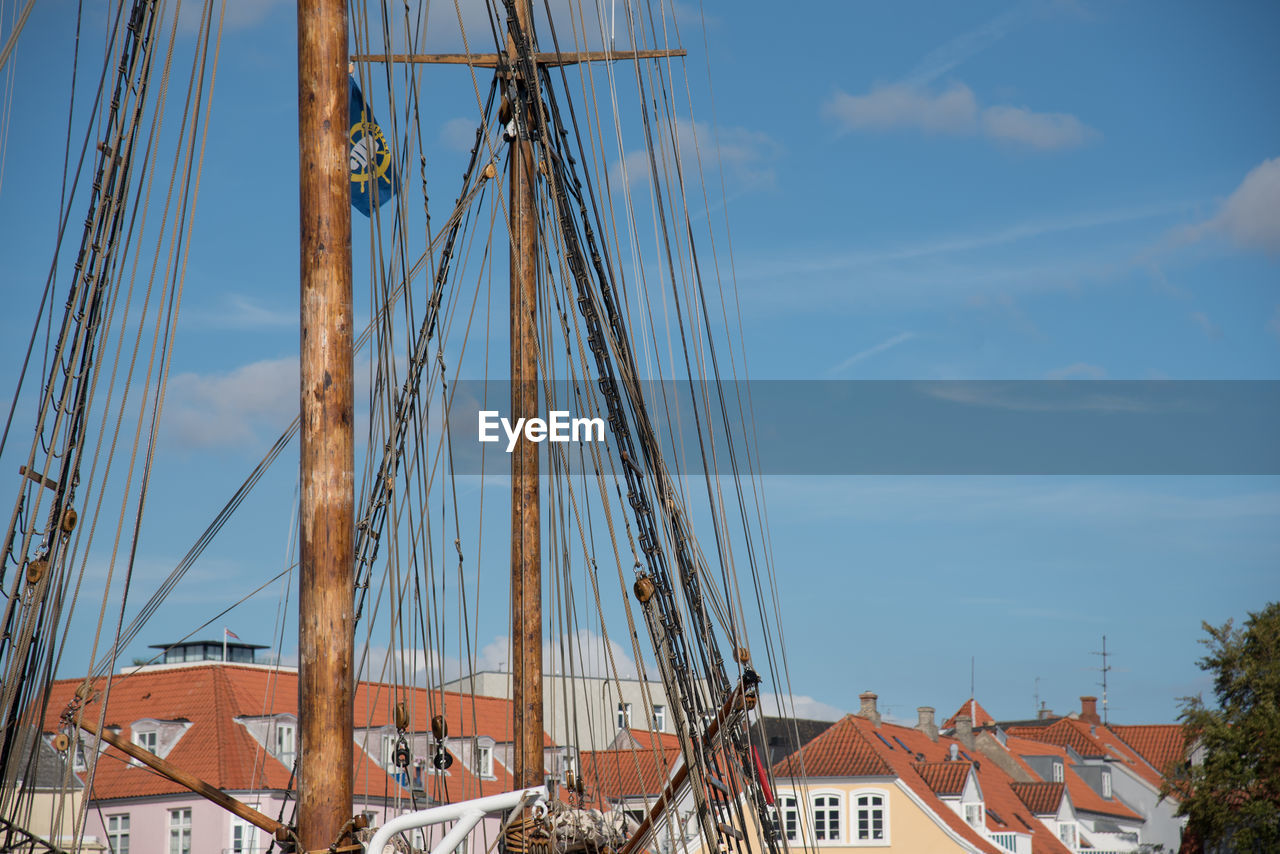 Sailing ship by houses against sky