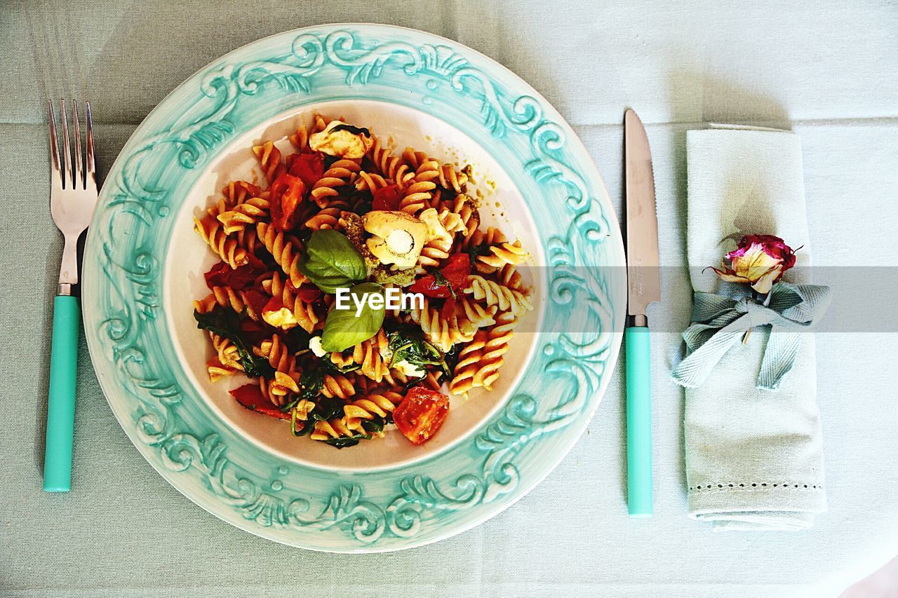 Directly above shot of pasta in plate amidst fork and table knife