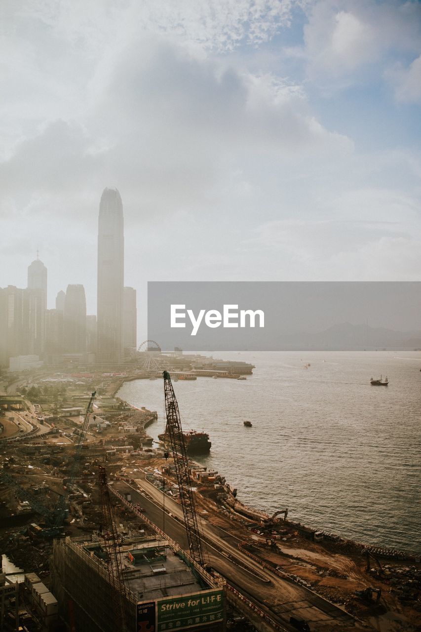 Aerial view of city by sea against sky