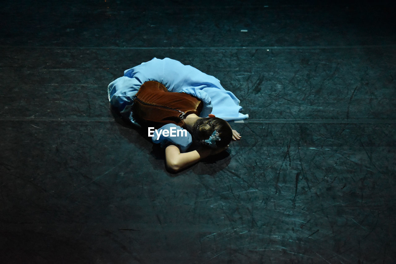 HIGH ANGLE VIEW OF WOMAN SITTING ON FLOOR AT HOME