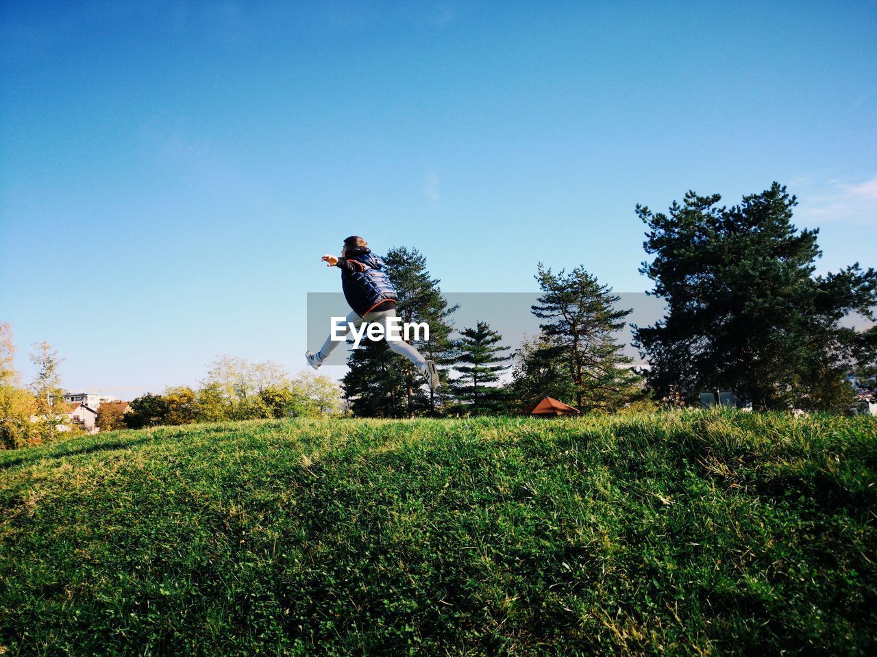 MAN JUMPING ON FIELD AGAINST TREES
