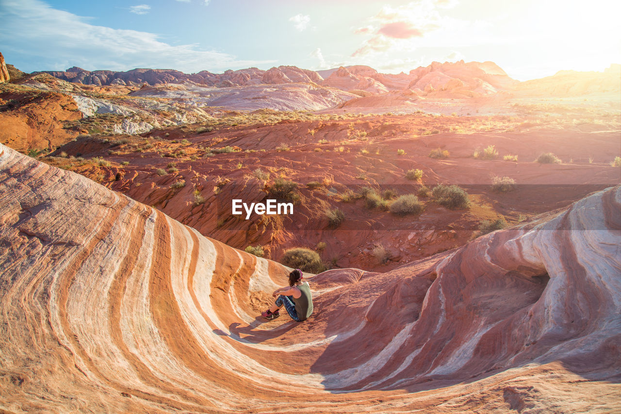 Woman sitting on mountain against sky