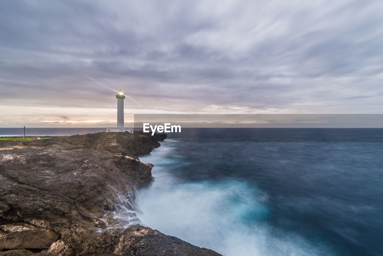 Lighthouse by sea against sky