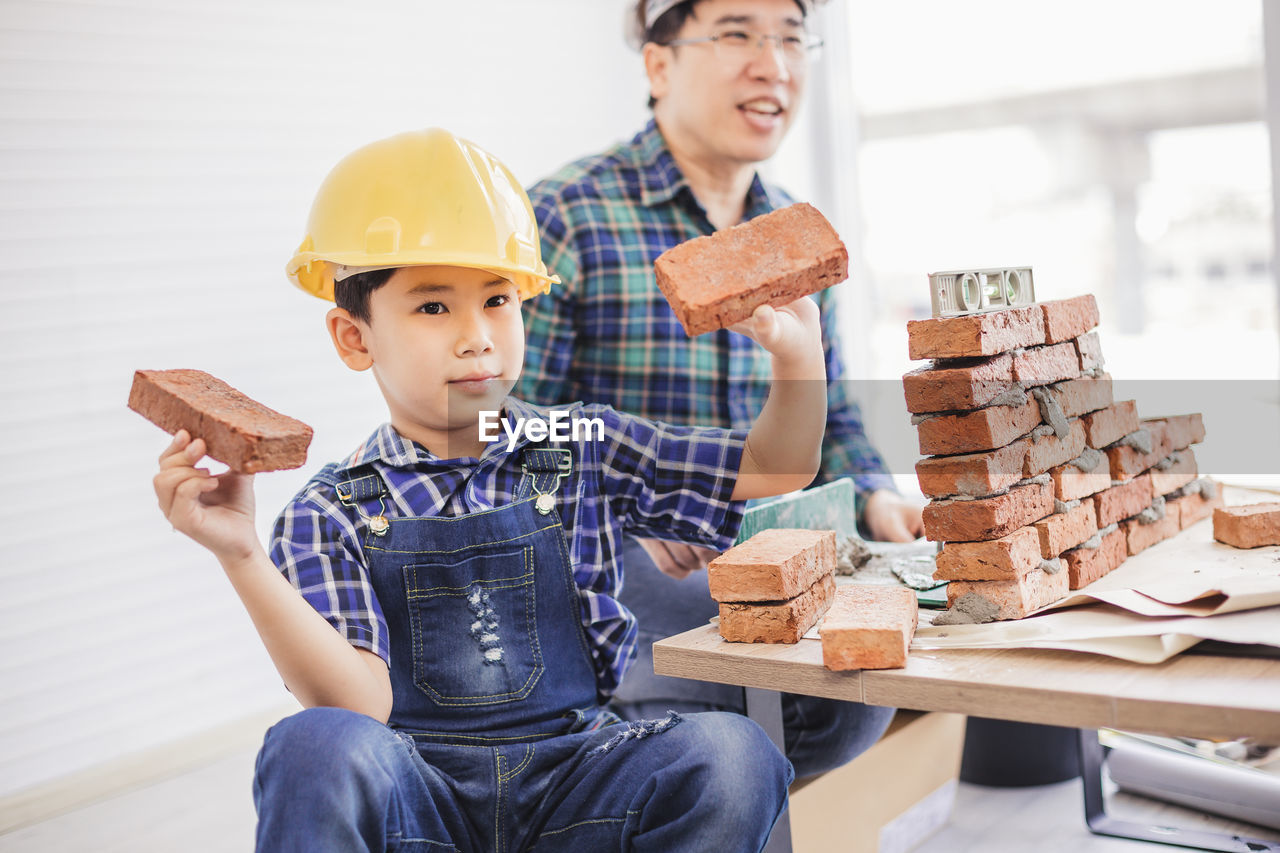 Father teaching son to make brick wall at workshop