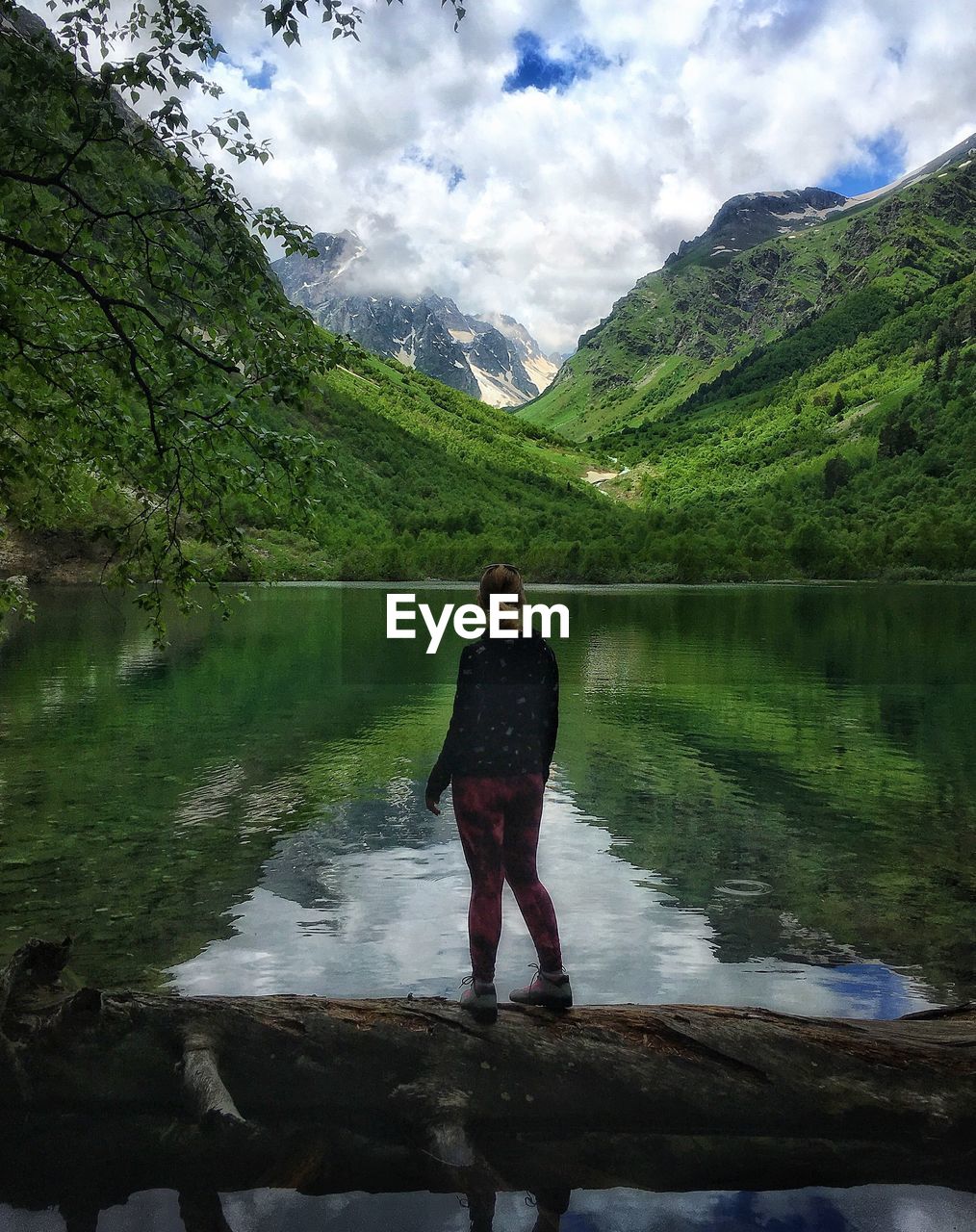 Rear view of woman standing at lake against sky