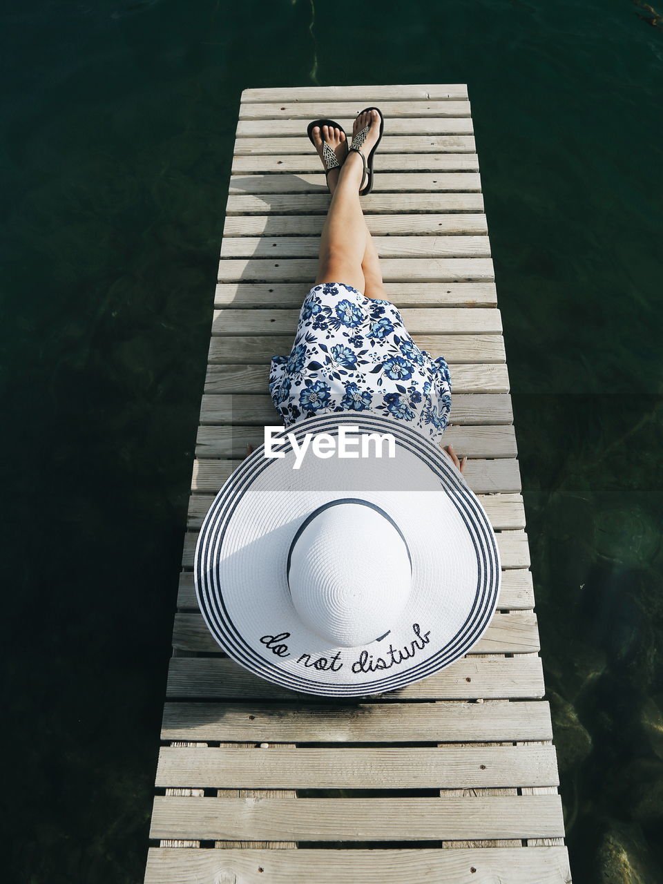 Woman in hat relaxing on pier over sea