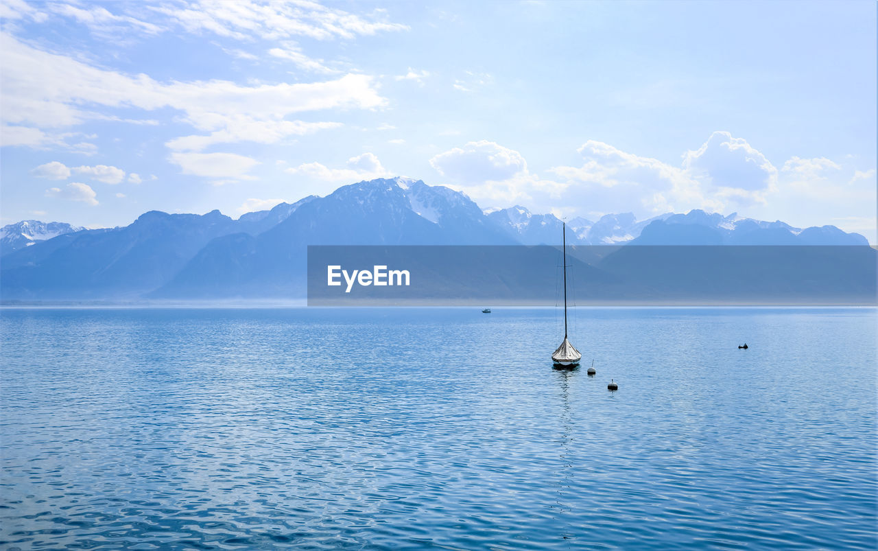 Sailboats in sea against mountains in montreux. switzerland. 