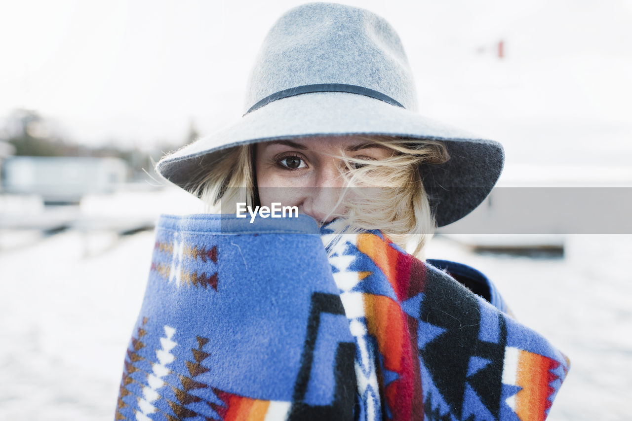Portrait of woman wrapped in blanket standing by lake simcoe