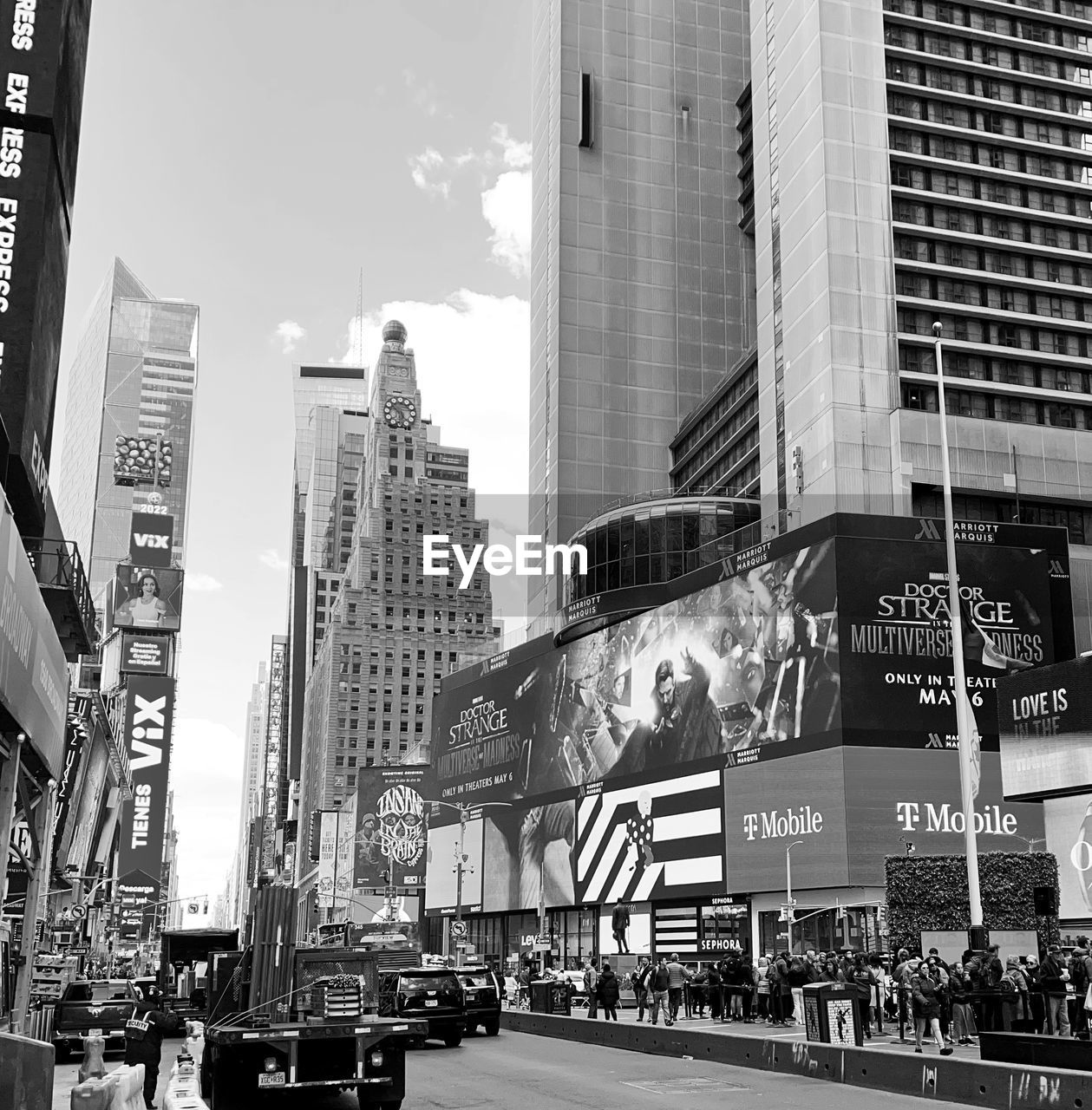 architecture, city, building exterior, built structure, black and white, road, metropolis, street, urban area, office building exterior, monochrome photography, monochrome, skyscraper, building, transportation, downtown, cityscape, mode of transportation, city life, car, motor vehicle, travel destinations, metropolitan area, infrastructure, black, office, sky, city street, skyline, vehicle, billboard, travel, sign, day, text, tower block, group of people, outdoors, land vehicle, nature, urban skyline, crowd, motion, communication, advertisement