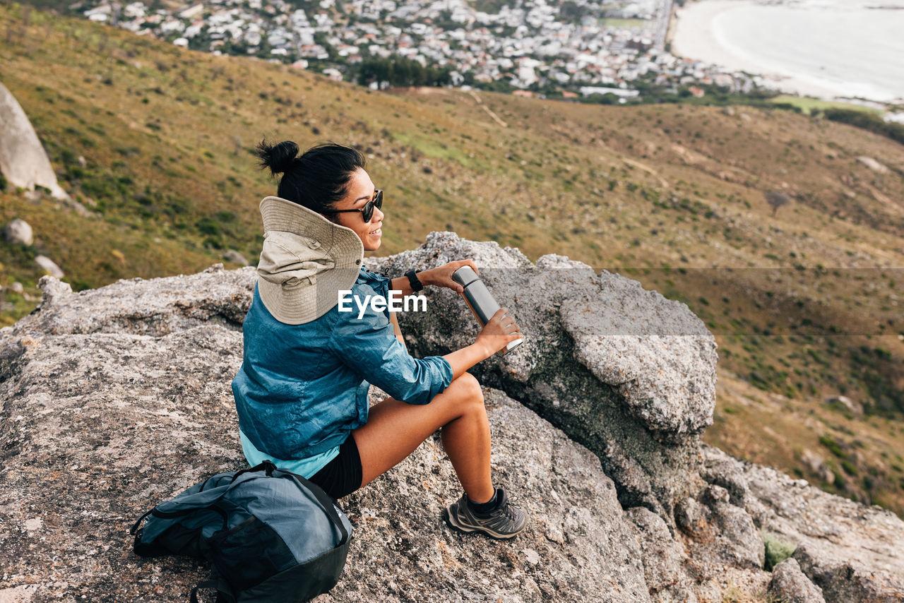 Side view of woman sitting on rock