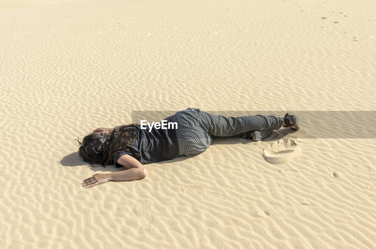 High angle view of woman lying on sand at beach