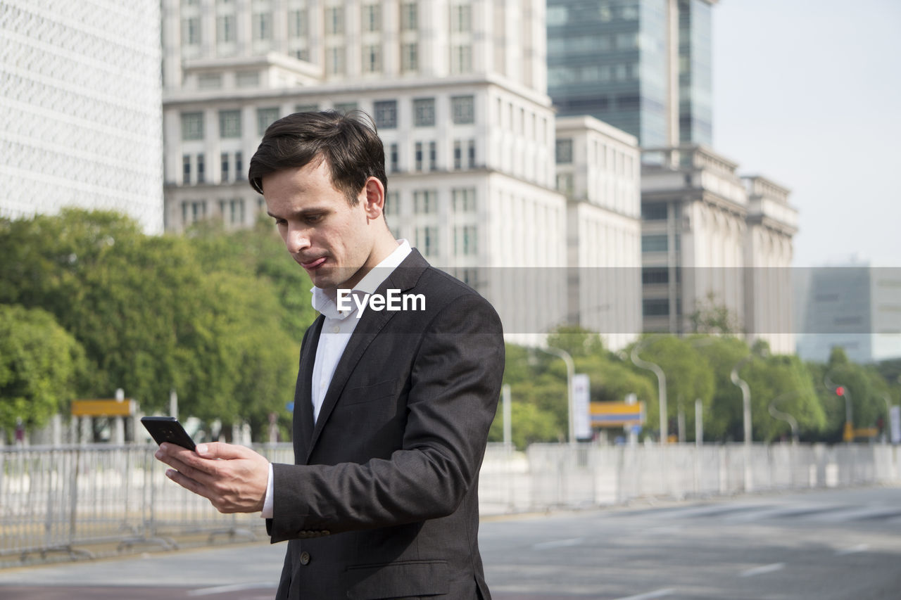 Young businessman using mobile phone in city