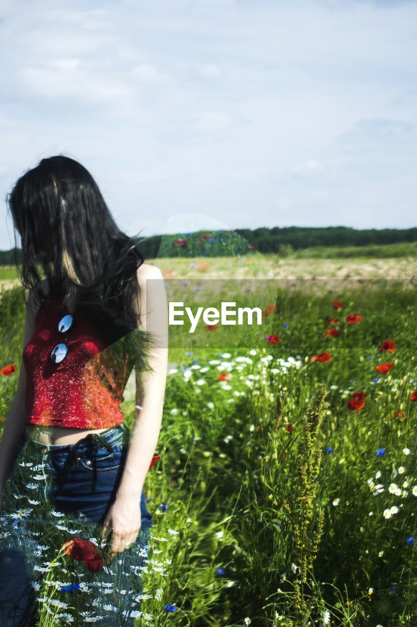 Young woman standing amidst plants against sky