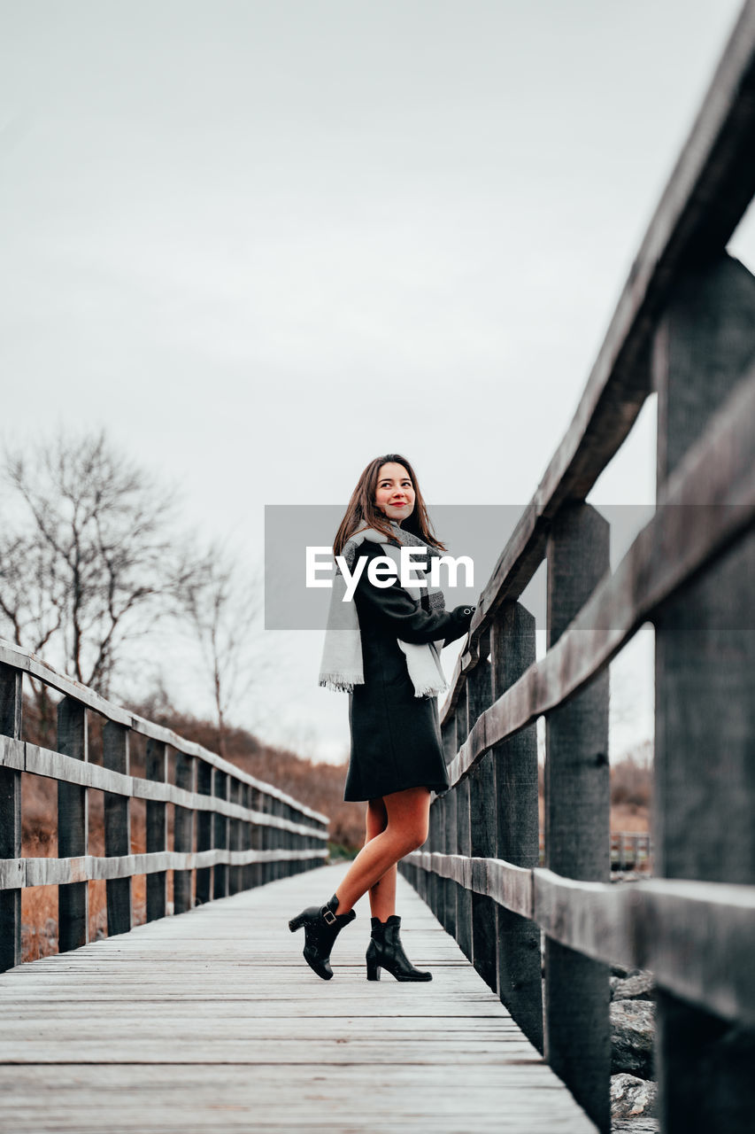 Side view of woman standing on footbridge