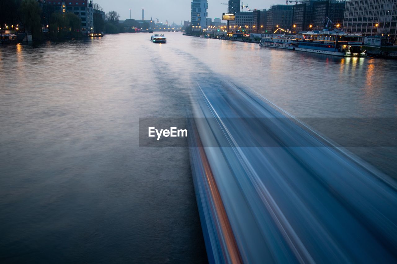 BLURRED MOTION OF ILLUMINATED CITY AT RIVER